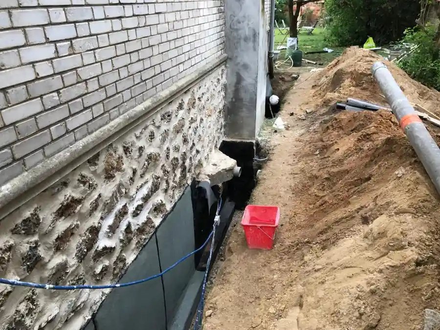 Étanchéité bitumineuse appliquée au pied d'un mur enterré, avec le drain périphérique